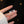 Butterfly-shaped earrings on a hand against a dark background