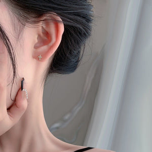 Close-up of an ear wearing a small earring with a neutral background