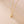 Gold necklace with a heart-shaped pendant on a beige background
