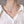 Gold necklace on a person wearing a white blouse against a neutral background