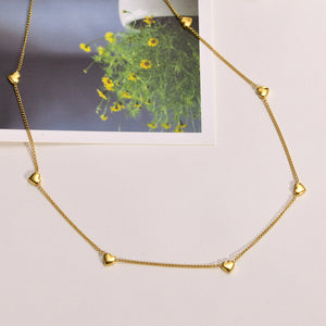 Gold necklace with heart-shaped pendants on a light background
