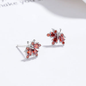 Butterfly-shaped earrings with red gemstones on a white background