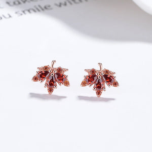 Rose gold earrings with red gemstones on a white surface