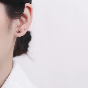 Close-up of an ear wearing a floral earring with a blurred background