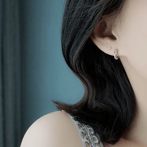 Close-up of a person wearing a silver hoop earring with a blurred background
