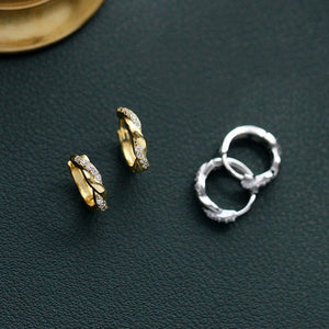 Gold and silver hoop earrings on a dark green surface