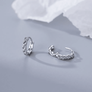 Pair of silver ear cuffs on a light gray background