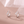 Silver earrings with star designs on a soft pink background