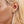Close-up of a woman's ear wearing a diamond earring with blonde hair.