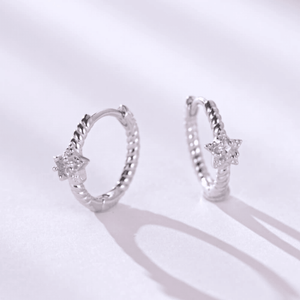 Pair of silver hoop earrings with star-shaped gemstones on a light gray background