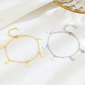 Gold and silver star-themed bracelets on a white surface with a crystal dish in the background.