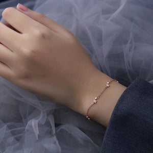 Two dainty star charm bracelets on a black background, one with a silver finish and the other with a gold plating finish.