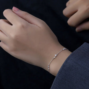 Two dainty star charm bracelets on a black background, one with a silver finish and the other with a gold plating finish.