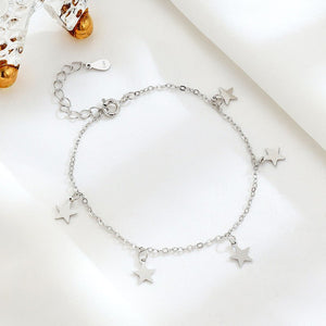 Two sterling silver bracelets with star charms, one with a gold plating, displayed on a white surface.