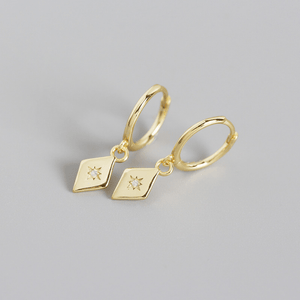 Gold hoop earrings with diamond-shaped charms on a gray background