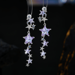 Star-shaped earrings with purple and silver stars on a dark background