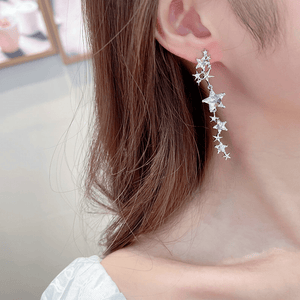 Star-shaped earrings worn by a person with a neutral background