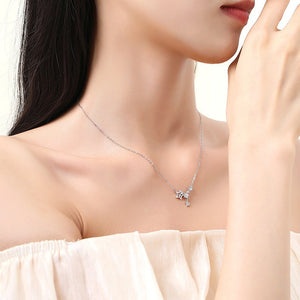 Woman wearing a silver necklace with a star pendant on a plain background