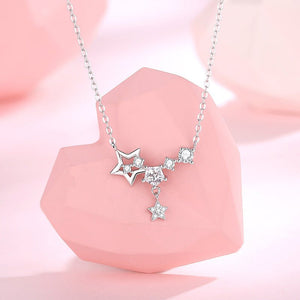 Silver star-shaped necklace on a pink stone with a soft pink background