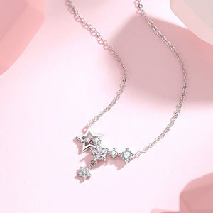 Silver necklace with star-shaped pendant on a pink background