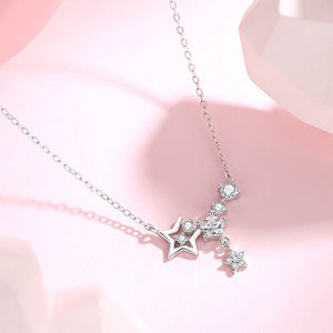 Silver necklace with star-shaped pendant on a pink background