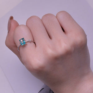 Model wearing a silver star ring with a green gemstone on a light blue background
