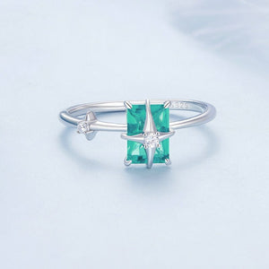 Silver star ring with a green gemstone on a light blue background