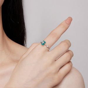 Model wearing a silver star ring with a green gemstone on a light blue background