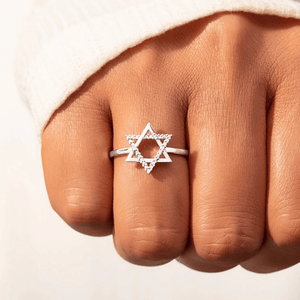 Silver Star of David ring on a person's finger against a neutral background
