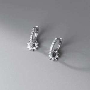 Pair of silver hoop earrings with clear gemstones on a gray background