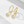 Gold hoop earrings with teardrop-shaped gemstones on a light background