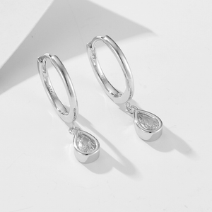 Silver hoop earrings with teardrop-shaped gemstones on a light gray background