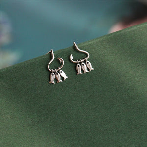 Silver fish-themed earrings on a green surface with a blurred background