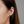 Close-up of an ear wearing a black heart-shaped stud earring with a blurred background