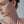 Close-up of a woman wearing a floral earring against a neutral background