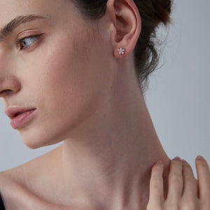 Close-up of a woman wearing a floral earring against a neutral background