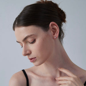 Woman wearing a small earring on a plain background