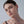 Close-up of a woman wearing a small earring against a plain background