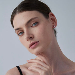 Close-up of a woman wearing a small earring against a plain background