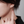 Close-up of an ear wearing a silver earring with a blurred background