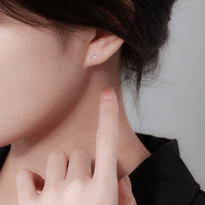 Close-up of an ear wearing a silver earring with a blurred background