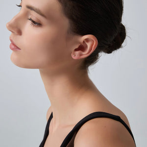 Close-up of a woman wearing a small earring on a plain background