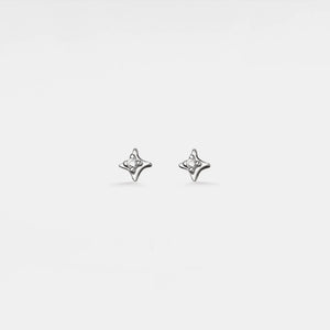 Pair of silver star-shaped earrings on a light gray background