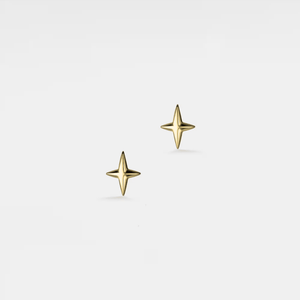 Gold star-shaped earrings on a light gray background
