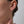 Close-up of an ear wearing a small stud earring with a blurred background
