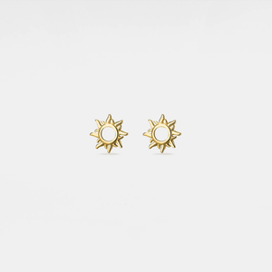 Gold sun-shaped earrings on a light gray background