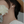 Close-up of an ear with a small earring, holding a white flower.