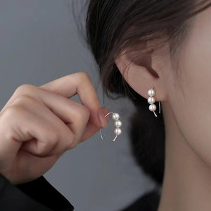 Person wearing pearl earrings with a neutral background