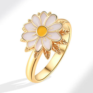 Gold ring with a white flower design on a white background