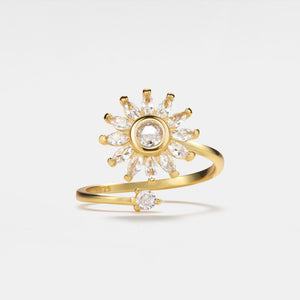 Gold ring with diamond sunburst design on a light gray background